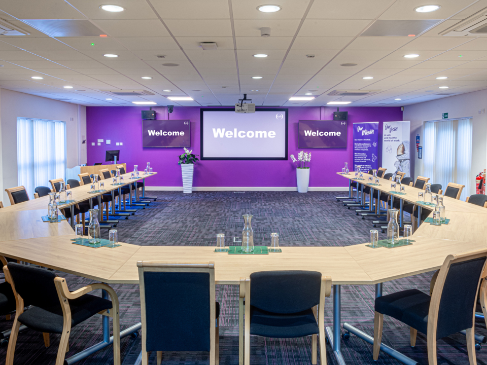 Conference room with table and chairs laid out in a horseshoe shape
