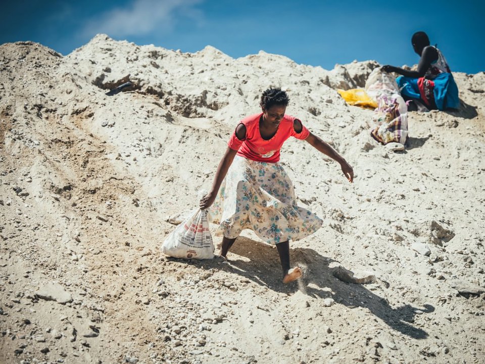 Woman dragging a bag of rocks she has scavenged in a quarry in kenya
