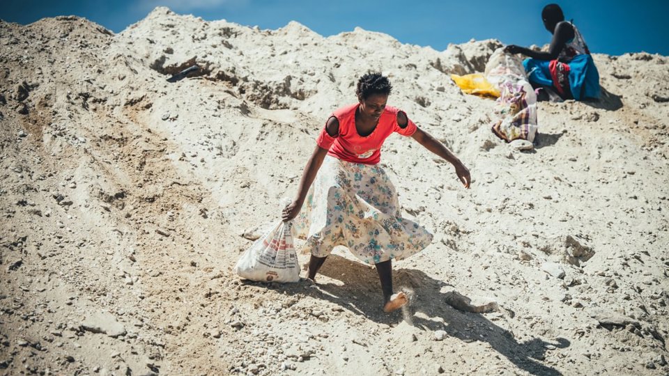 Woman dragging a bag of rocks she has scavenged in a quarry in kenya