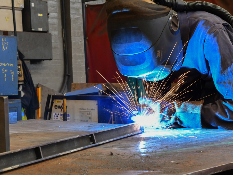 Worker wearing personal protective equipment doing some welding 