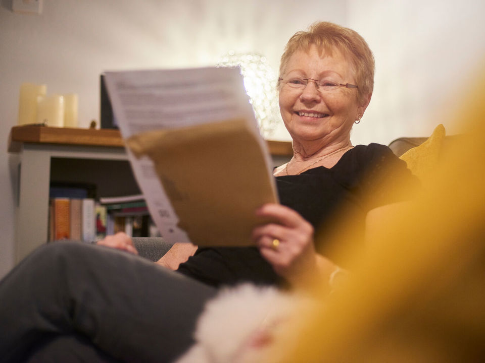 Smiling woman in armchair reading a letter
