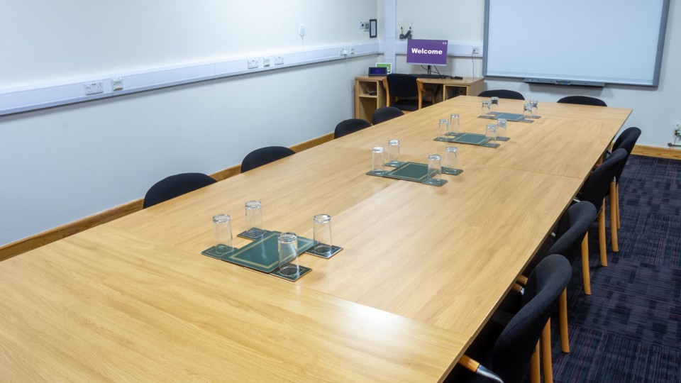 Long rectangular table with chairs around it in meeting room