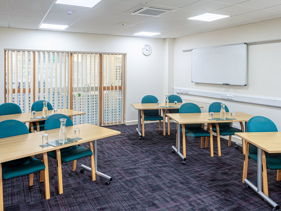 Meeting room laid out like a classroom, two chairs behind each desk