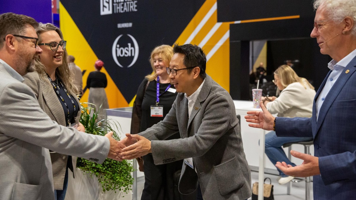 Men shaking hands in group of people at Health and Safety Event