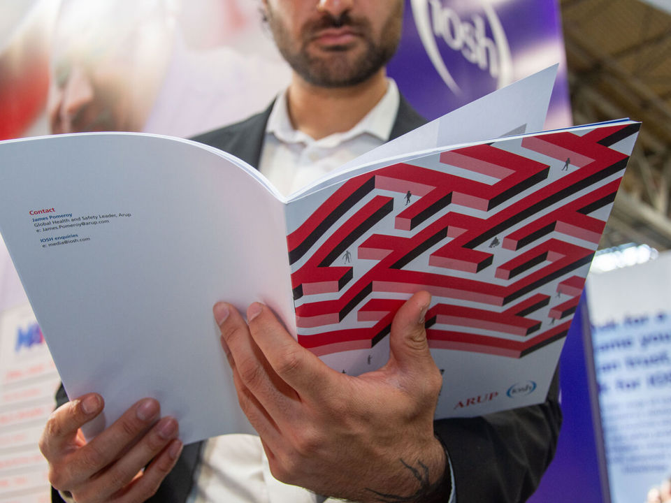 Man in suit reading report IOSH logo in background