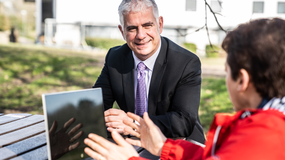 Two people sitting outside at table talking