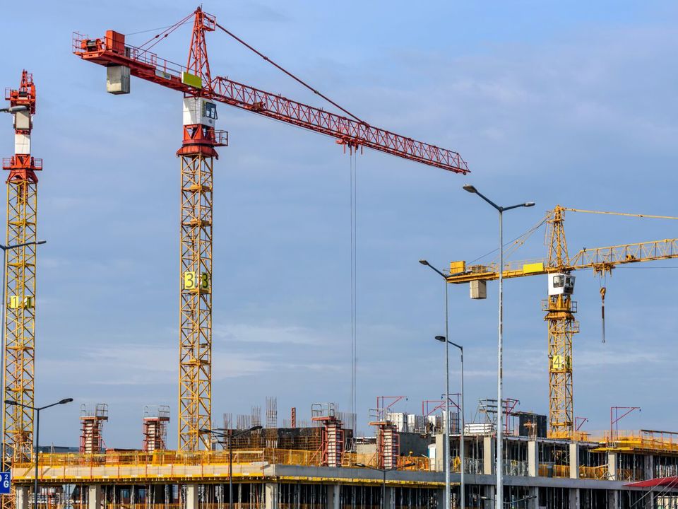Three towering cranes on building site