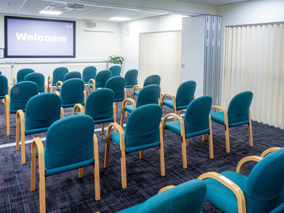 Meeting room laid out with rows of chairs for a presentation
