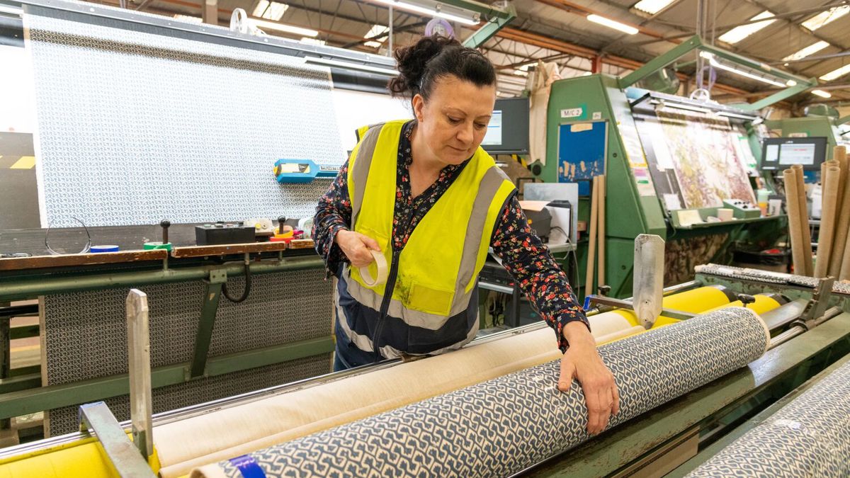 Worker examining roll of fabric in factory