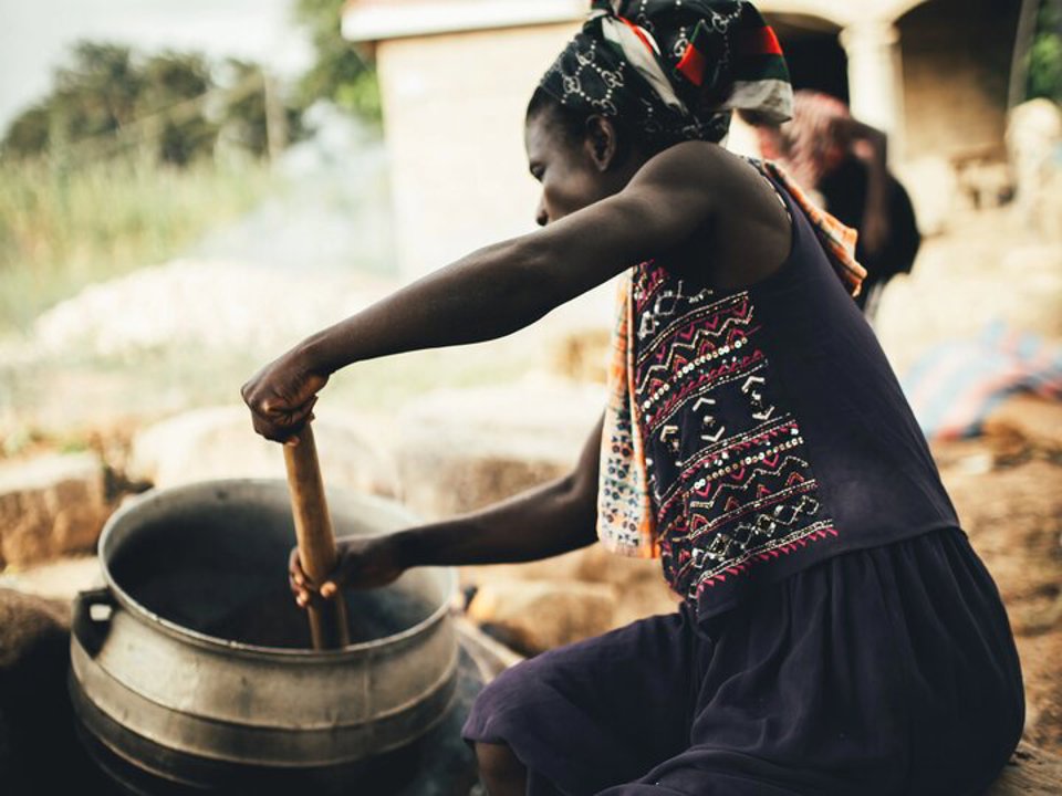 Female worker stirs a pot containing the shea butter mush