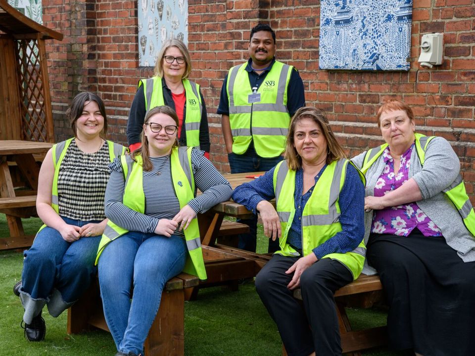 Group of workers in high-vis vests sitting on picnic bench