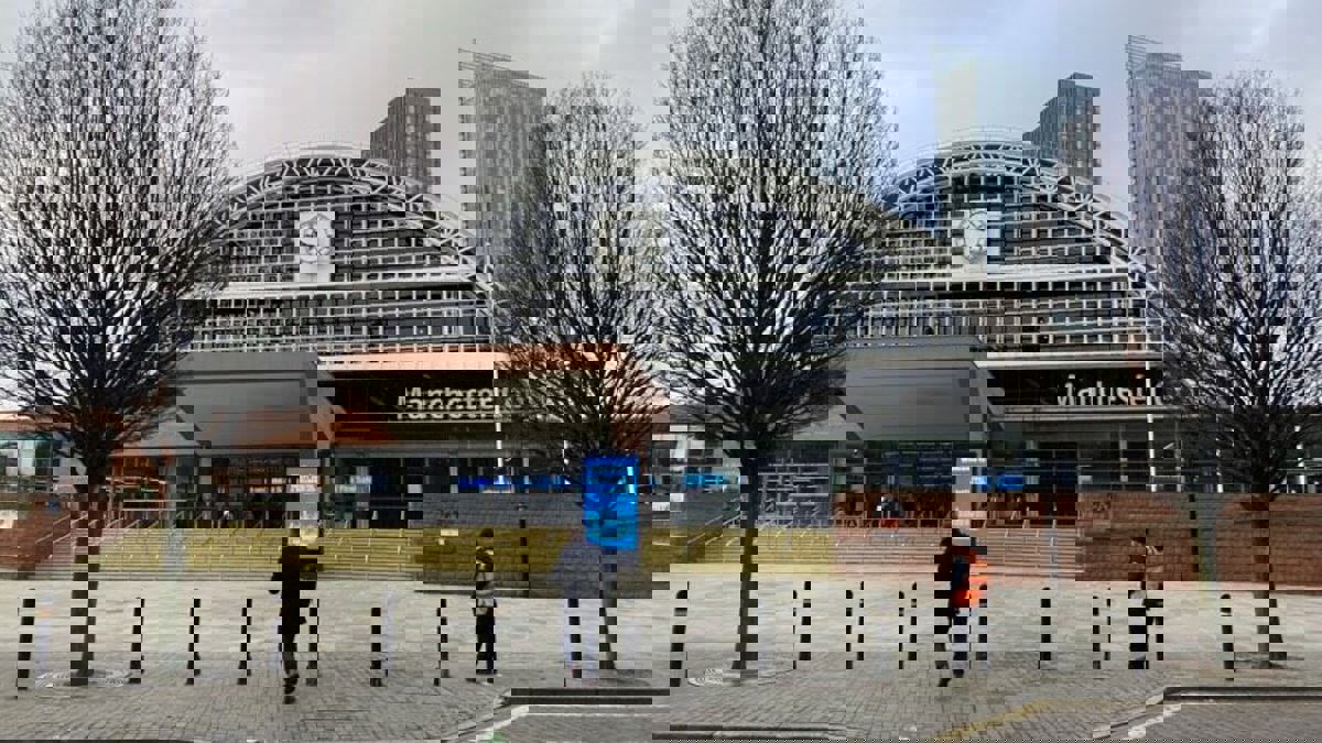 Front view of Manchester Central Convention Complex with people walking outside on an overcast day.