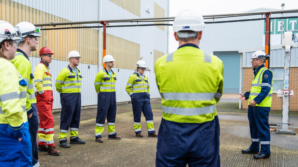 People in hard hats and high vis vests standing in a circle