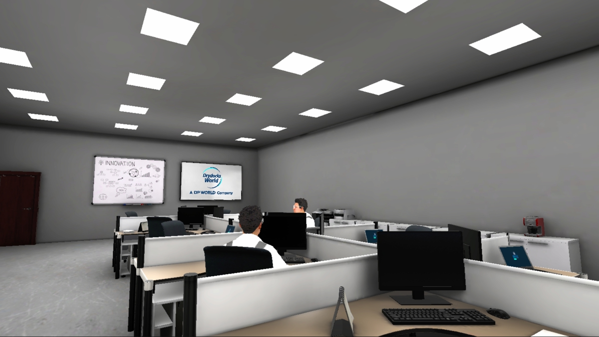 VR training scene in a modern office with rows of desks, computer monitors, and two people seated. Two screens at the front display “INNOVATION” and “Drydocks World.” Bright ceiling lights and a closed door are visible.