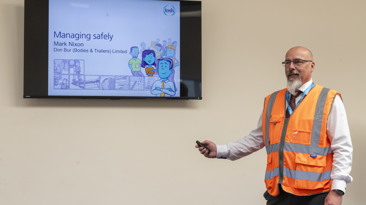 Mark Nixon delivering an IOSH Managing Safely training presentation at Don-Bur, standing beside a screen displaying course content.