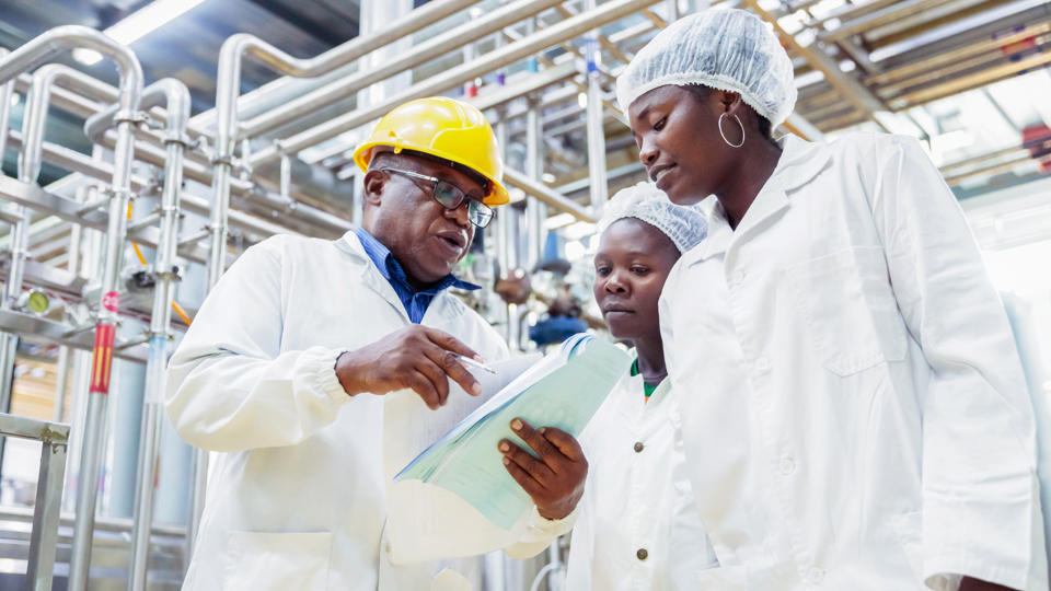 Male factory manager with workers looking at checklist