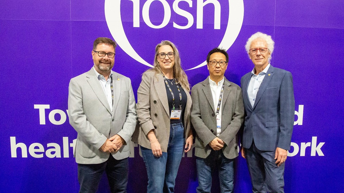 Four IOSH volunteers in standing in front of IOSH logo