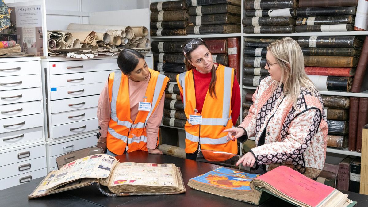 Group of three people looking at book of historic fabric prints