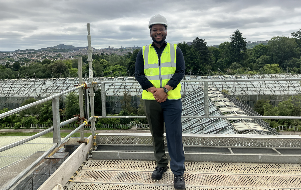 Caleb standing in front of a building wearing a hi-vis vest