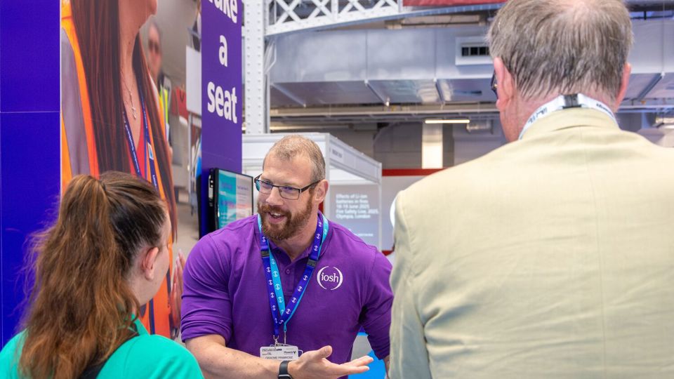 IOSH staff member answering a question at the conference stand
