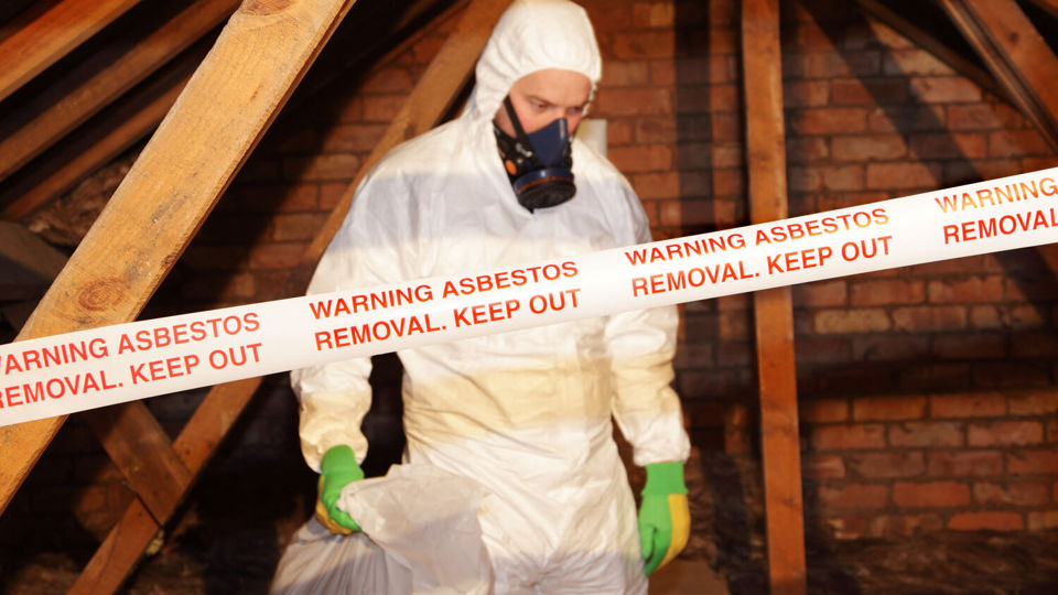 Hand placing asbestos warning label
